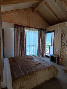 a bedroom with a large bed and a large window at Belvedere in Ambrolauri