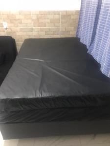a bed with a black sheet on top of it at Apartamento Toninhas in Ubatuba