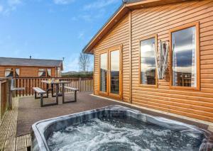 una bañera de hidromasaje en una terraza junto a una casa en Scottish retreat en Banchory