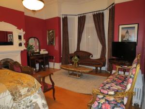 a living room with red walls and a bed and a tv at The Roses Heritage Inn in St. John's