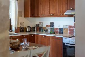 a kitchen with wooden cabinets and a table with glasses on it at Villa Calliope St George Retreat BY APOKORONAS-VILLAS in Kókkinon Khoríon +44 photos