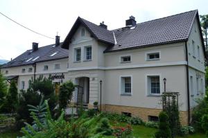 une grande maison blanche avec un toit noir dans l'établissement Gościniec Zapiecek, à Stronie Śląskie