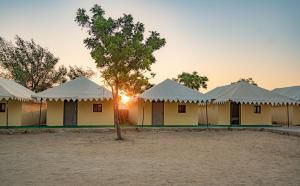 a row of white tents with a tree in the foreground at Dynasty Desert Camp and Resort in Sām