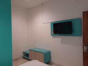 Habitación con TV en una pared blanca en Cozy centre Simpang Lima Semarang en Semarang