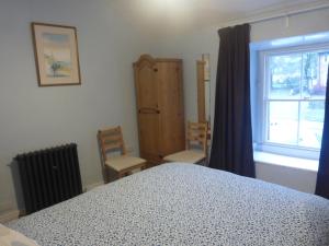 a bedroom with a bed and two chairs and a window at Lyndale House in Bradwell
