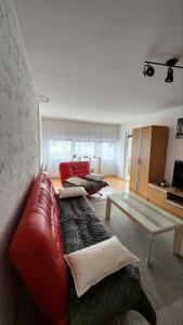 ein Wohnzimmer mit einem roten Sofa und einem Tisch in der Unterkunft Apartman Airport in Sarajevo