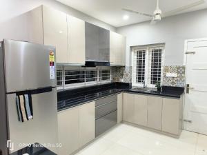 a kitchen with white cabinets and a stainless steel refrigerator at Peppercorn Cottage, Vythiri. in Vythiri