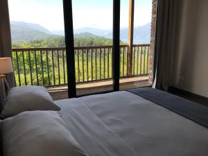 a bedroom with a bed and a large window with a view at Agriturismo Voeuja Lago Maggiore in Luino