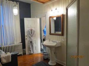 a bathroom with a sink and a robe hanging on the door at The Roses Heritage Inn in St. John's +101 photos