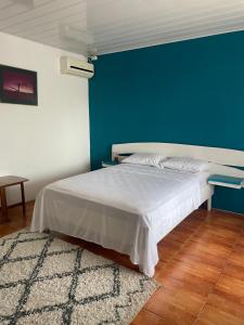 a bedroom with a bed with a blue wall at Cómodo dormitorio in Quepos
