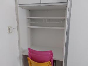 a pink chair sitting next to a white closet at PEQUENO QUARTO individual-PERTO DO CENTRO DE CONVENÇÕES-FENEARTE - RECIFE - ventilador,TV,mesa de trabalho in Recife