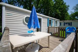 einen Tisch mit einem Sonnenschirm und zwei Stühlen auf einer Terrasse in der Unterkunft Camping des Bains in Saint-Honoré-les-Bains