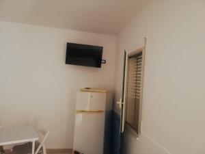 a room with a refrigerator and a television on the wall at Calliope in Marsala