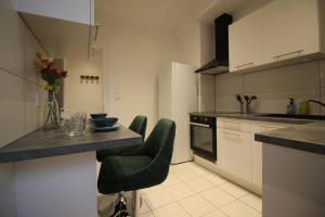 a kitchen with a counter and some green chairs at Nouveau - Le Shilichic - Gare in Schiltigheim