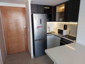 eine Küche mit einem Kühlschrank aus Edelstahl und einer Mikrowelle in der Unterkunft Apartamento Nuevo Mall y metro Plaza Egaña in Santiago