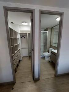 a bathroom with two doors and a toilet and a sink at Apartamento Nuevo Mall y metro Plaza Egaña in Santiago