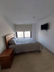een slaapkamer met een bed en een flatscreen-tv bij Apartamento Nuevo Mall y metro Plaza Egaña in Santiago