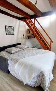 a bedroom with a bed and a wooden staircase at Maisonnette in La Croix-en-Touraine