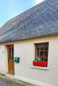 una casa bianca con una finestra e una pentola di fiori di Maisonnette a La Croix-en-Touraine