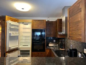 eine Küche mit einem weißen Kühlschrank und Holzschränken in der Unterkunft Residence Cry d'Err, Rte de Vermala 41, 4BR in Crans-Montana