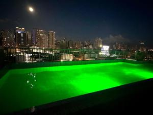 a green swimming pool with a city skyline at night at City Nest Makati with Rooftop pool and Free Netflix in Manila