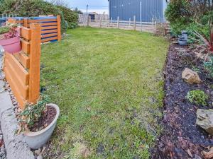 a backyard with a yard with a fence and plants at Hynish House in Stornoway