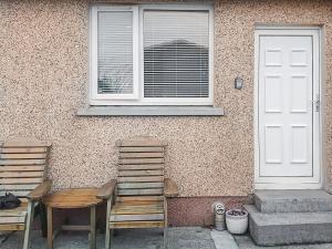 zwei Stühle vor einem Gebäude mit Fenster in der Unterkunft Hynish House in Stornoway