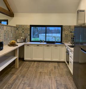 a kitchen with white cabinets and a large window at Gîte de la Forge, l'Atelier in Fléré-la-Rivière