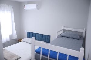 1 dormitorio con cama blanca y ventana en Cobertura Enseada de Zimbros, en Bombinhas