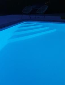 una piscina por la noche con luces azules en Chalet Mésange, en Érezée