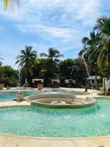 a fountain in the middle of a pool with palm trees at Palmarito Beach Hotel in Tierra Bomba