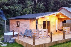 une cabane en rondins avec une terrasse et une table dans l'établissement Luxury log cabin with wood fired hot tub, à Moville