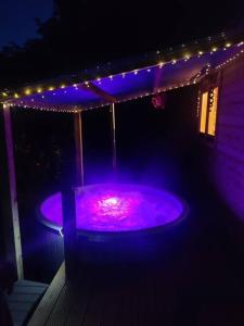 un bain à remous violet avec des lumières sur une maison dans l'établissement Luxury log cabin with wood fired hot tub, à Moville