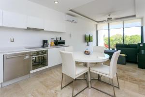 una cucina e un soggiorno con tavolo e sedie bianchi di Menesse-2bedrooms-PerfectSpot steps to the ocean a Playa del Carmen