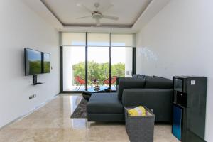 un soggiorno con divano nero e TV di Menesse-2bedrooms-PerfectSpot steps to the ocean a Playa del Carmen