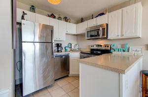 a kitchen with white cabinets and a stainless steel refrigerator at 0208 Tiki Tower by Atlantic Towers in Carolina Beach