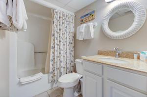 a bathroom with a toilet and a sink and a mirror at 0208 Tiki Tower by Atlantic Towers in Carolina Beach
