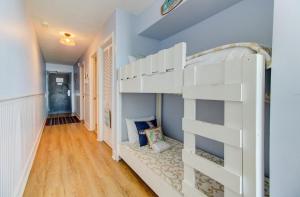 a white bunk bed in a room with blue walls at 0208 Tiki Tower by Atlantic Towers in Carolina Beach