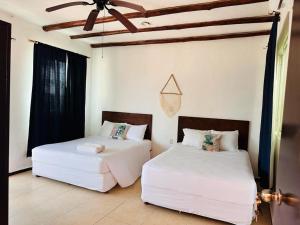 2 witte bedden in een kamer met een plafond bij Hotel Arenas Mahahual in Mahahual