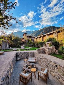 a backyard with a stone wall and tables and chairs at AVA Valle Sagrado Spot in Urubamba
