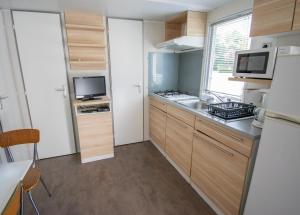 a small kitchen with a sink and a microwave at Camping des Bains in Saint-Honoré-les-Bains