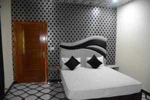 木爾坦的住宿－Hotel The Taj Multan，一间卧室配有一张带黑白枕头的床