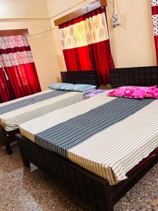 two beds in a room with red curtains at Sirvachur madhurakalli amman guest house in Perambalūr