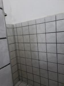 a bathroom with white tiled walls and a shelf at Pousada Point da Nanda in Juazeiro do Norte +42 photos