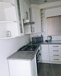 een keuken met witte kasten en een fornuis met oven bij Bakoena's full house in Newcastle