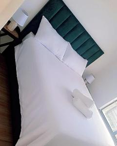 een bed met witte kussens en een groen hoofdeinde bij Bakoena's full house in Newcastle