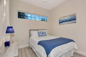 a white bedroom with a bed and two windows at Courtyard Home with Pool, Spa & Sauna close to Beach & City Center in Sarasota