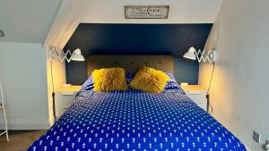 Una cama azul con almohadas amarillas en un dormitorio en Westgate Garden riverside, en Canterbury
