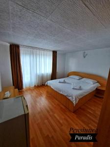 1 dormitorio con 1 cama y suelo de madera en Pensiunea Paradis, en Buşteni