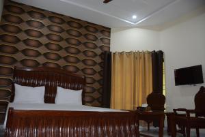 a bedroom with a wooden headboard and a bed at Hotel The Taj Multan in Multan